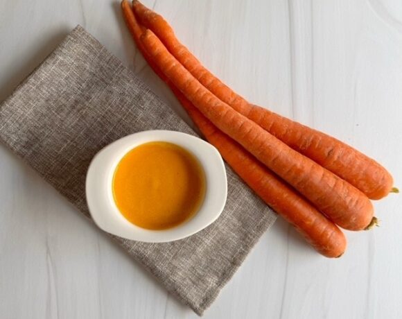 Napkin with white ramakin filled with creamy orange ginger miso salad dressing and 3 carrots on the side.